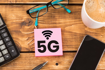 desk with paper 5G wlan and smartphone, glasses, coffee and calculator