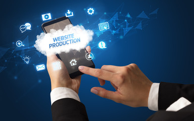 Female hand holding smartphone with WEBSITE PRODUCTION inscription, cloud technology concept