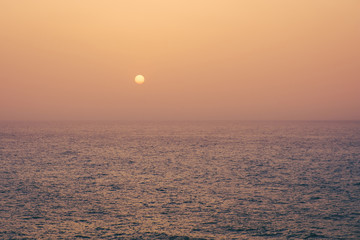Fototapeta premium sunset on water, sun going down behind ocean