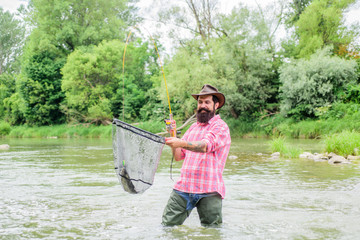 Bearded brutal fisher catching trout fish with net. If fish regularly you know how rewarding and...