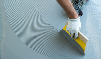 construction worker renovates balcony floor and spreads watertight resin and glue - obrazy, fototapety, plakaty