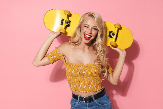 Image of positive young woman with red lipstick wearing summer clothes smiling and holding skateboard