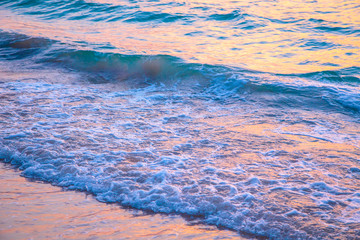 sunset on the sea. sandy beach, clear water, waves. surf line in the warm colors of the setting sun.