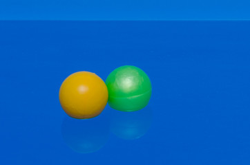 two plastic balls of yellow and green, lie in a pool of water.