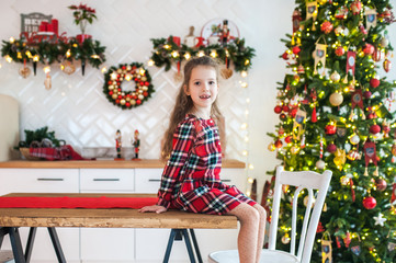 Portrait of a girl sitting in the kitchen decorated for Christmas