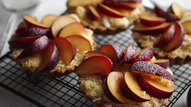 Homemade crumble tarts with fresh plum slices placed on iron baking grill