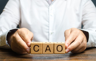 Man holds the word CAO in hands. Chief Accounting Officer. Vacancy and duties of a specialist. Manage taxes and payroll. Develop and upgrade finance systems in business. financial executives,
