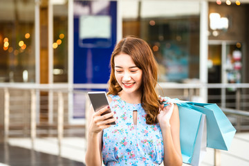 Young asian shopper woman use smartphone with shopping bags