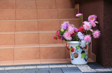 Piękna kolorowa dekoracja z kolorowych kwiatów i wiaderka na schodach domu.