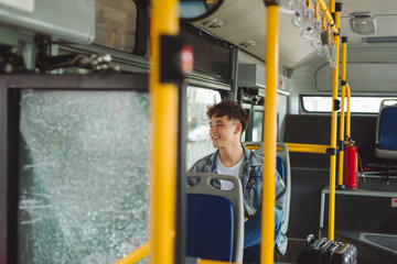 Asian man taking public transport, sitting inside city bus.