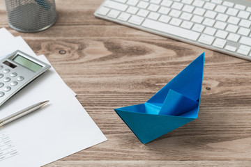 Office workspace with blue paper ship
