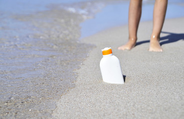 Baby's legs on sand and protection sun cream.