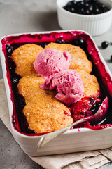 Raspberries and black currants cobbler with raspberry ice cream in baking dish. Homemade fruit pie pastries. Gray vintage background. Top view.