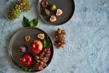 Assortment healthy organic fruits in plates apple grapes fig plums tangerines