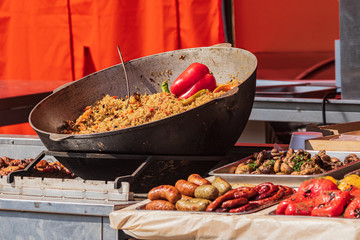 Culinary buffet with takeaway healthy food - plov, rice, meat, pepper, spices, grilled vegetables. Fish and meat on the street, food market, festival, event. Kitchen in the open air.