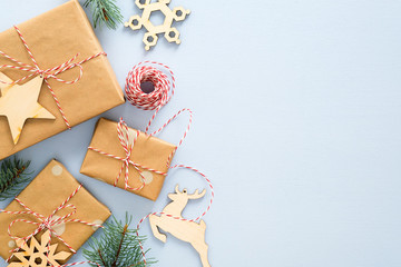 Christmas or winter composition. Frame made of gifts box wrapped kraft paper, twine rope, wooded Xmas decorations, fir tree branches on pastel blue background. Christmas, winter, new year concept