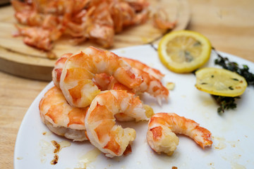 cooked and peeled tiger prawn shrimps with garlic, lemon and herbs on a white plate, selected focus, narrow depth of field