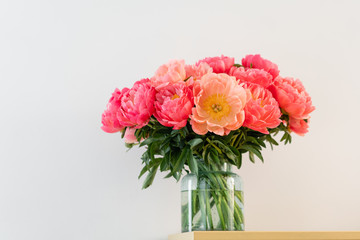 Coral peonies in a glass vase on wooden table.. Beautiful peony flower for catalog or online store. Floral shop concept . Beautiful fresh cut bouquet. Flowers delivery. Copy space