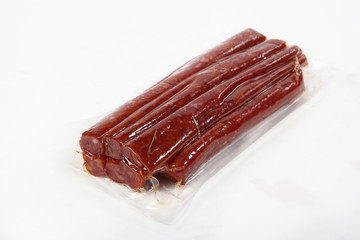 Sun-dried vacuum-packed sausage. View from above. Isolated object. Copy space.