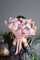 Pink peonies in womans hands. Beautiful peony flower for catalog or online store. Floral shop...