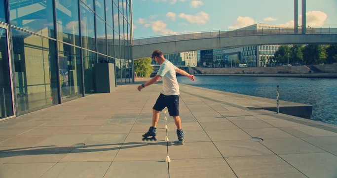 Handsome man on roller skates doing beautiful tricks and spins in city location with sun flares 