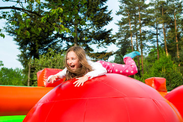 Happy little girl having lots of fun on a inflate castle while jumping.