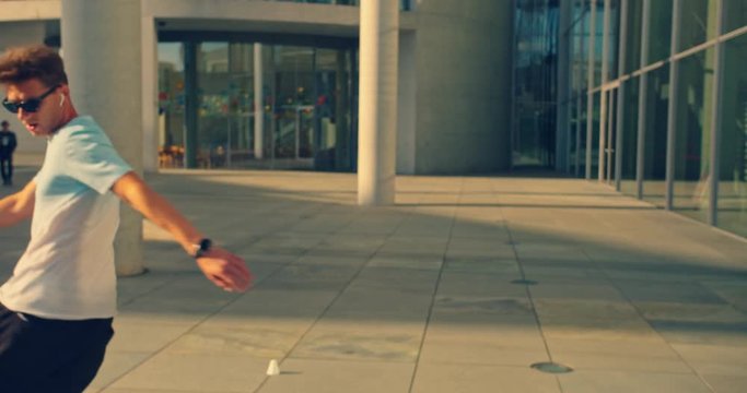 Handsome man on roller skates doing beautiful tricks and spins in city location with sun flares 