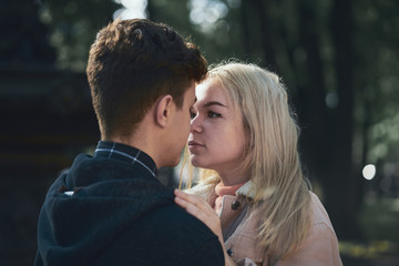 Man and woman look at each other, young couple full of love in autumn Park. Concept of teen love and happiness