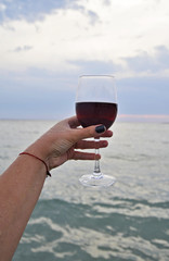 Wineglass with red wine on the beach at sunset. Romantic concept.