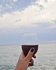 Wineglass with red wine on the beach at sunset. Romantic concept.