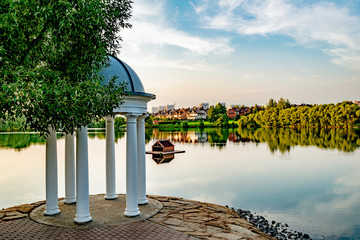  Round arbor in the classical style on the banks of the pond in the park