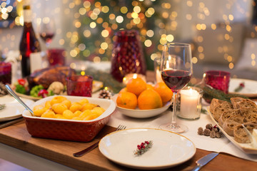 christmas dinner and eating concept - glass of red wine and food on table at home