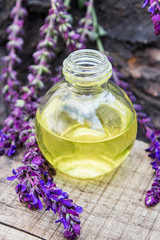Obraz na płótnie Canvas Lavender essential oil in a glass bottle on a wooden table near the branches of blooming lavender. Tincture or essential oil with lavender. herbal medicine.