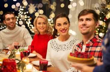 holidays and celebration concept - happy friends having christmas dinner at home