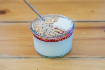   "Malabi" on a wooden table - "Malabi" is  the Israeli ultimate dessert ! milk pudding that served with rose water and sugar syrup , nuts and grounded coconut. 