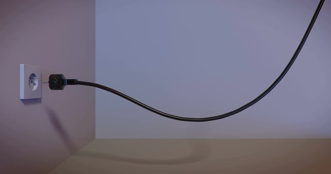 220V electric plug inserted in electric wall socket. Power cord plugging into outlet.