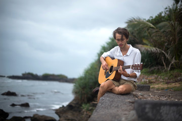 Romantic young man with a guitar on the beach