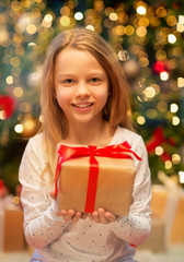 christmas, holidays and childhood concept - smiling girl with gift box at home