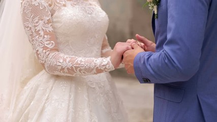Close-up of the hands of the newlyweds on the wedding day. The groom gently strokes his bride's hand, close-up.