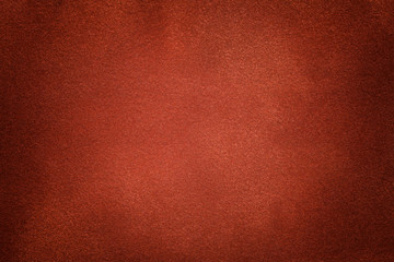Background of dark orange suede fabric closeup. Velvet matt texture of ginger nubuck textile