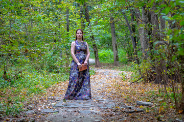 Obraz premium A middle-aged woman stands on the path in the autumn Park.