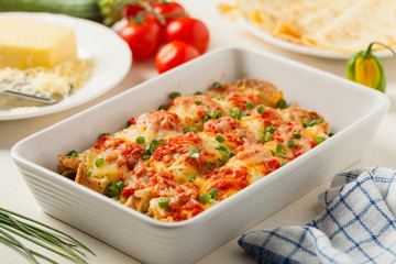 Baked pancakes with chicken in tomato sauce.