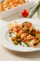 Baked pancakes with chicken in tomato sauce.