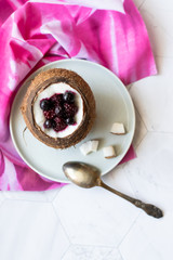Berry dessert with yogurt in a cup of coconut on a light background. Blackberries, raspberries, blueberries, black currants. Pink napkin
