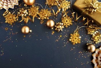 christmas or new year decorations background in gold colors on dark grey background with empty copy space for text. holiday and celebration concept for postcard or invitation. top view