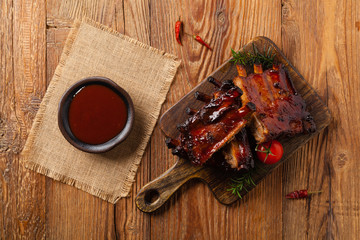Roasted pork ribs in a bbq sauce. Served on a wooden board. Top view.