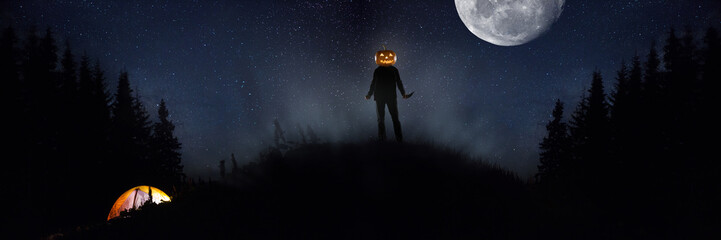 Halloween theme: scary maniac with pumpkin head in dark forest on sky background with midnight moon. People in camping don't know what the danger. Horrible fantasy. October, horror concept.