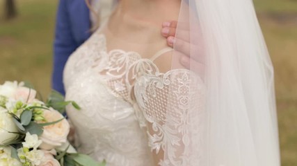 Happy newlyweds in love walk in a green summer Park, they stand hugging. Portrait of embracing newlyweds outdoors, they are enjoying each other.