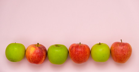 Ripe juicy apples of new crop. Group of colorful apples in line isolated on pink background with copy space for your text. Symbol of healthy lifestyle. Fruits rich in vitamins, iron. Harvest festival.
