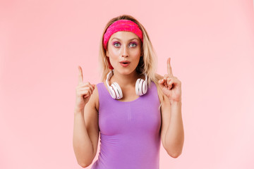 Image of nice surprised woman pointing fingers upward with headphones